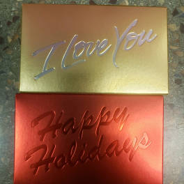 Two metallic gift boxes reading "I Love You" and "Happy Holidays"