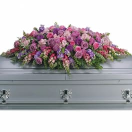 Lavender and pink floral casket spray on a gray casket