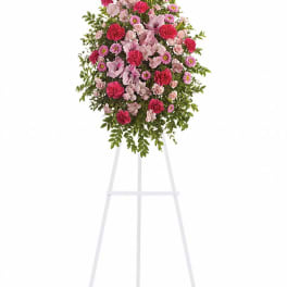 Standing floral spray of pink and magenta flowers on a white easel