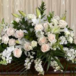 Large white and blush floral casket spray with lilies and roses