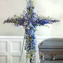 Blue floral cross on a stand beside a casket