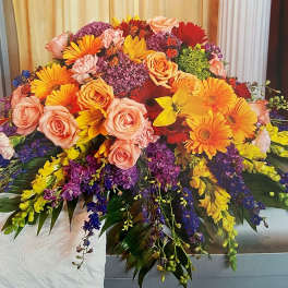 Large colorful floral arrangement with roses, gerbera daisies, and purple blooms