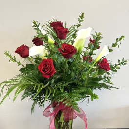 Bouquet of red roses and white calla lilies in a glass vase