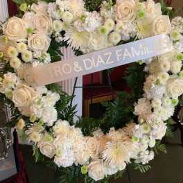 White floral heart wreath with a memorial ribbon on an easel