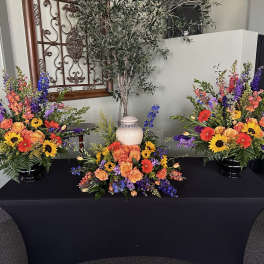 Three colorful floral arrangements on a black-draped table