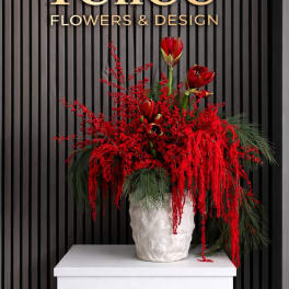 Red floral arrangement in a white textured vase