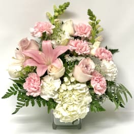 Pink and white floral arrangement in a square glass vase