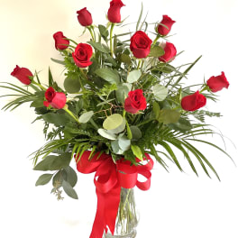 Bouquet of red roses in a clear glass vase with a red ribbon