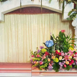 Floral arrangements with pink, purple, and white flowers on a stage with columns