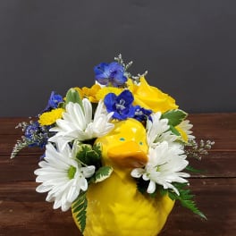 Yellow duck-shaped vase with white daisies and blue flowers