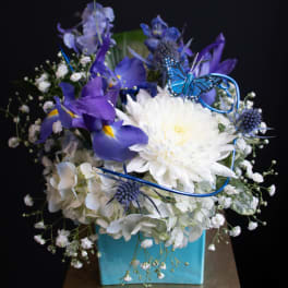 Blue and white floral arrangement in a turquoise box with a butterfly accent