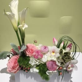 Pink and white floral arrangement in a white rectangular container
