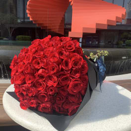 Large bouquet of red roses wrapped in black paper
