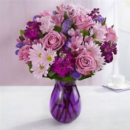 Pink and purple bouquet in a purple glass vase