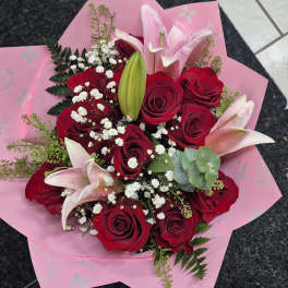 Bouquet of red roses and pink lilies wrapped in pink paper