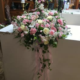 Large pink and white floral arrangement with trailing ribbon