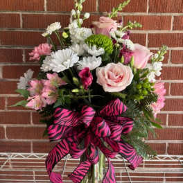 Pink and white mixed flower bouquet in a glass vase with a zebra-print ribbon