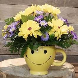Yellow and purple flowers in a smiley-face mug vase