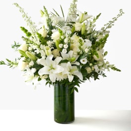White lilies and roses arranged in a tall glass vase