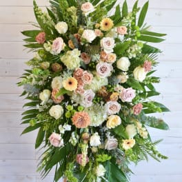 Large standing spray of pastel roses and mixed flowers with tropical greenery