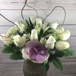White roses and purple ornamental cabbage in a vase arrangement