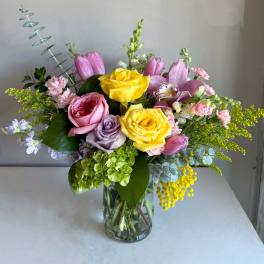 Mixed bouquet of pink and yellow flowers in a clear glass vase