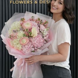 Woman holding a large pastel bouquet wrapped in pink paper