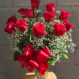 Bouquet of red roses with baby's breath in a glass vase and red ribbon