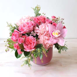 Pink rose and orchid arrangement in a pink vase
