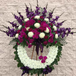 Standing floral wreath with purple orchids and white flowers on an easel