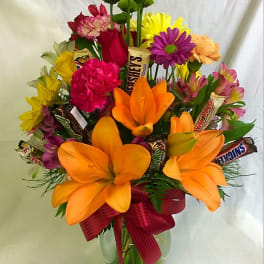 Bright mixed bouquet with orange lilies and assorted flowers in a glass vase