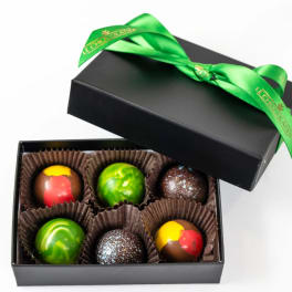 Black gift box of six colorful round chocolates with a green ribbon on the lid