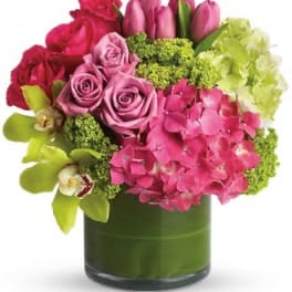 Pink and red flower arrangement in a green glass vase
