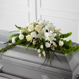 White floral spray arranged on a gray casket