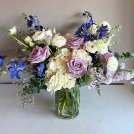 Lavender roses and white blooms in a clear glass vase