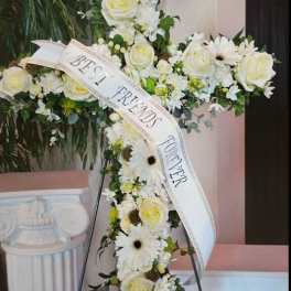 Standing floral cross of white roses and gerbera daisies with a Best Friends Forever ribbon.