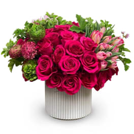 Hot pink roses and tulips arranged in a ribbed white vase