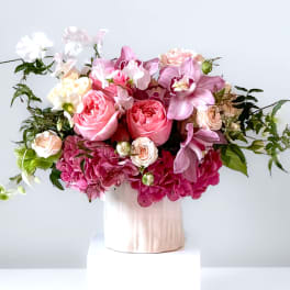 Pink and white floral arrangement in a pale vase