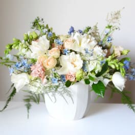 White and peach floral arrangement in a white vase