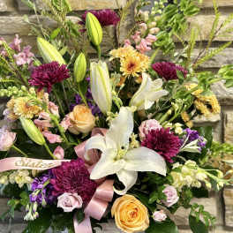 Mixed bouquet in a white basket with lilies, roses, and chrysanthemums