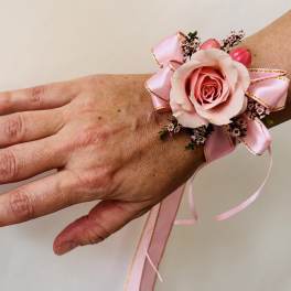 Pink rose wrist corsage with ribbon on a person's hand