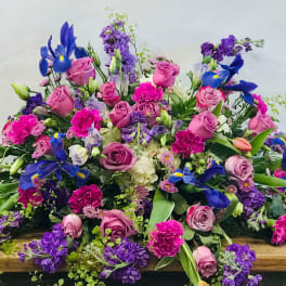 Large mixed bouquet of pink, purple, and blue flowers on a wooden surface