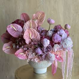 Pink floral arrangement in a white vase with anthuriums and peonies