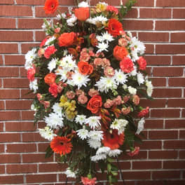 Standing floral spray with orange and white flowers on a black easel