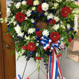 Large standing wreath of red, white, and blue flowers on an easel
