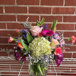 Mixed bouquet in a glass vase with pink, purple, and green flowers
