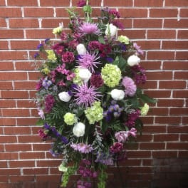 Large standing floral spray with purple, white, and green blooms