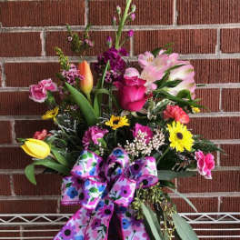 Colorful mixed flower arrangement with a large patterned ribbon