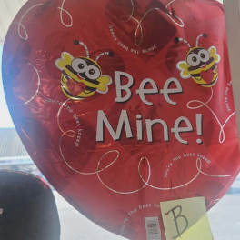 Red heart-shaped balloon with cartoon bees and the words "Bee Mine!"