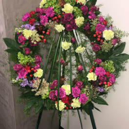 Large floral wreath on an easel with pink, yellow, and purple blooms